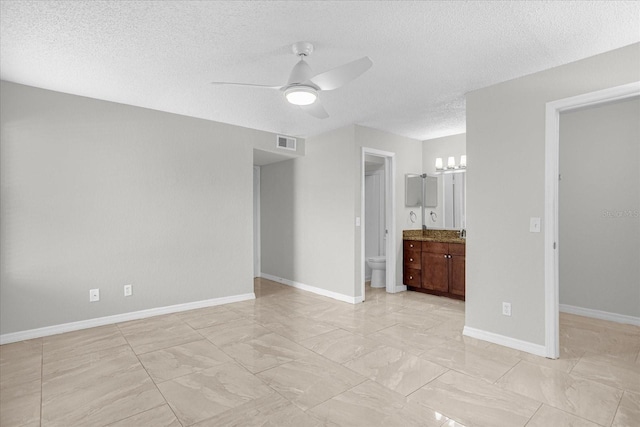 interior space featuring a textured ceiling, ensuite bath, and ceiling fan