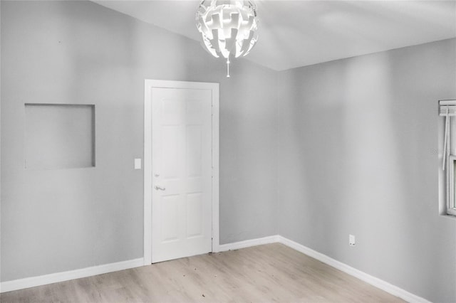 empty room with an inviting chandelier and light hardwood / wood-style flooring