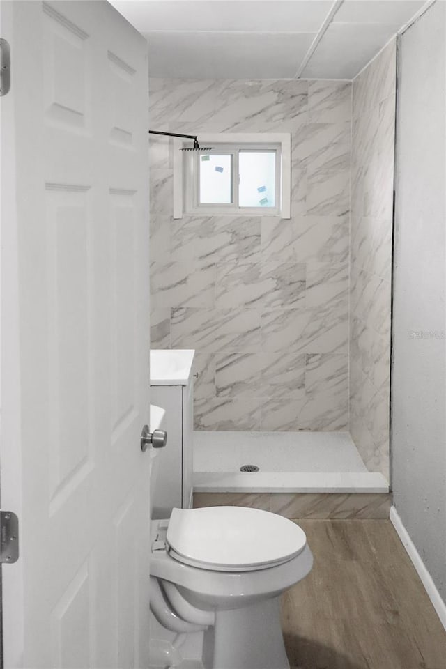 bathroom with tiled shower, hardwood / wood-style floors, and toilet