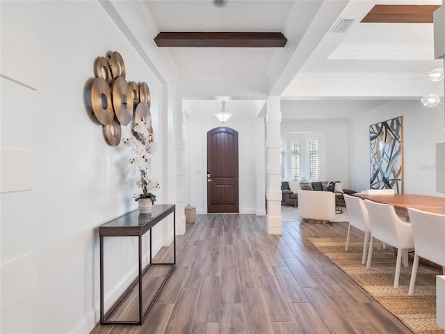 entrance foyer featuring light wood-type flooring, ornamental molding, and beamed ceiling