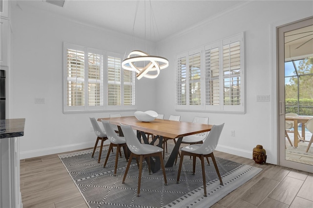 dining room featuring light hardwood / wood-style floors, a healthy amount of sunlight, a notable chandelier, and ornamental molding