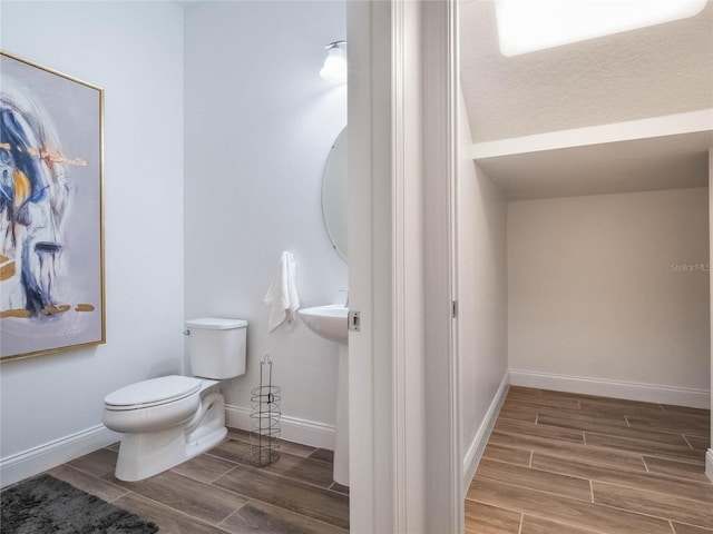 bathroom with toilet, wood-type flooring, and a textured ceiling