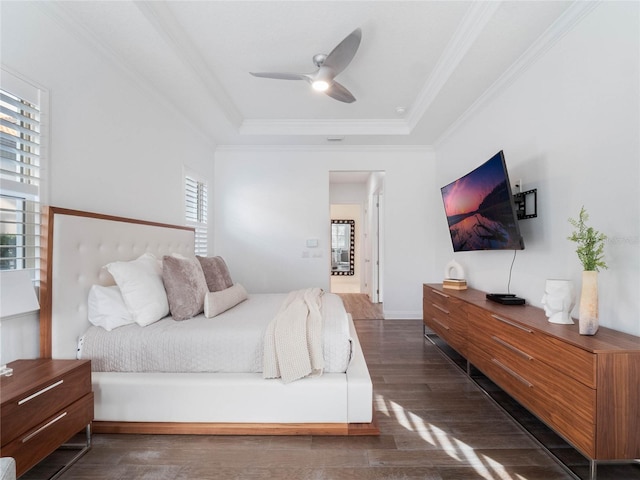 bedroom with ceiling fan, a raised ceiling, dark hardwood / wood-style floors, and crown molding