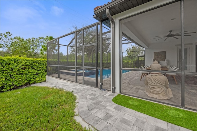 view of swimming pool with ceiling fan, glass enclosure, and a patio area