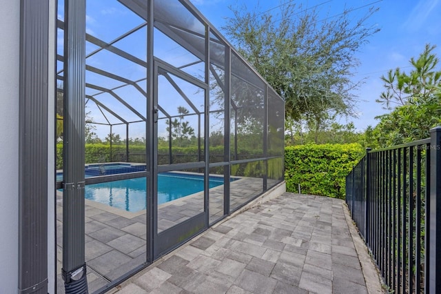 view of swimming pool featuring an in ground hot tub, glass enclosure, and a patio area