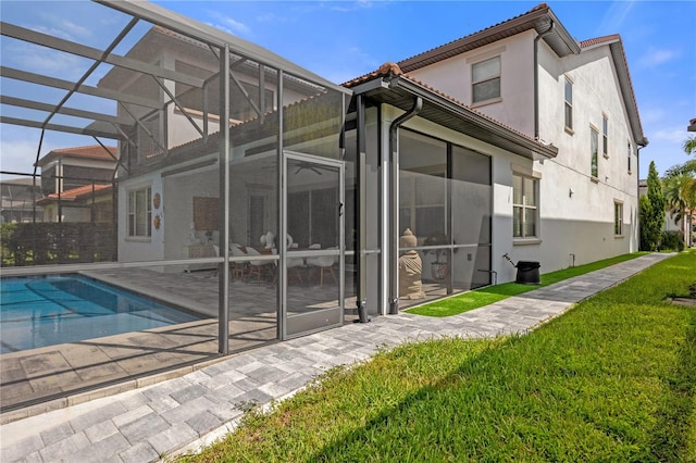 rear view of property with a patio, a yard, and glass enclosure