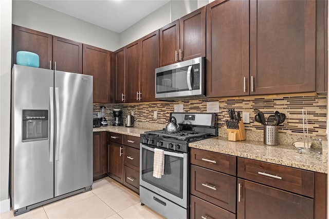 kitchen with decorative backsplash, dark brown cabinetry, light stone countertops, and appliances with stainless steel finishes