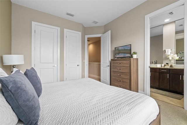 bedroom with ensuite bath and light carpet