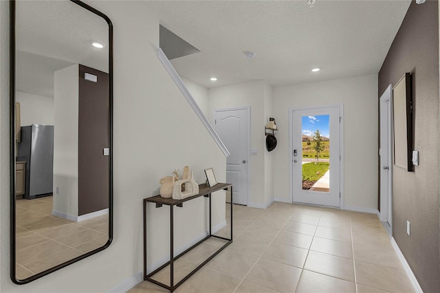 foyer entrance featuring a textured ceiling and light tile patterned floors