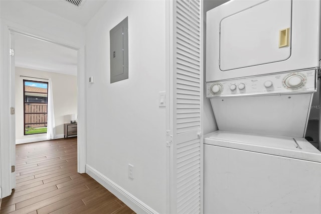 clothes washing area featuring electric panel, hardwood / wood-style floors, and stacked washer and clothes dryer