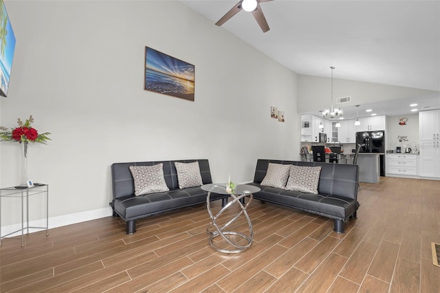 living room with vaulted ceiling, hardwood / wood-style floors, and ceiling fan with notable chandelier