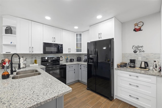 kitchen with wood-type flooring, sink, white cabinetry, and black appliances