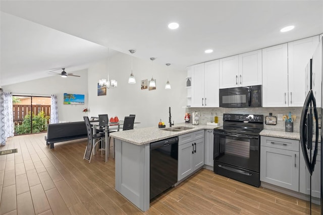 kitchen with kitchen peninsula, sink, vaulted ceiling, and black appliances