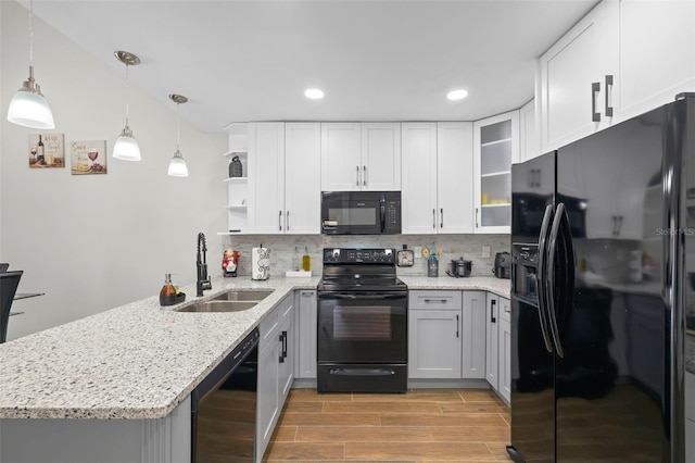 kitchen featuring kitchen peninsula, tasteful backsplash, black appliances, white cabinetry, and hanging light fixtures