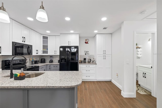 kitchen with light stone countertops, pendant lighting, white cabinets, and black appliances