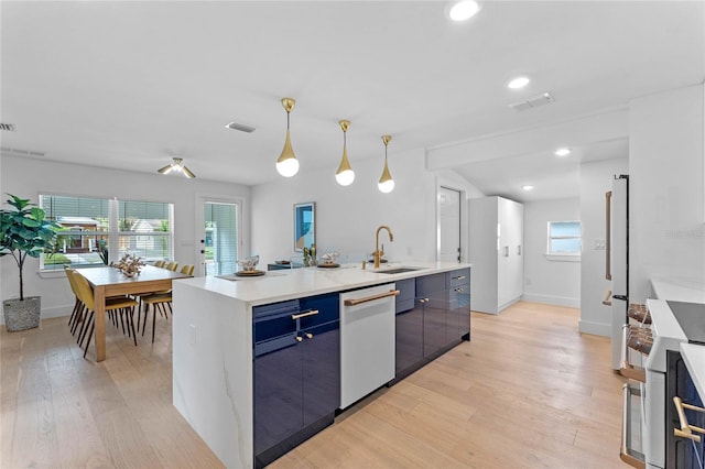 kitchen featuring dishwasher, a center island with sink, hanging light fixtures, light hardwood / wood-style floors, and range