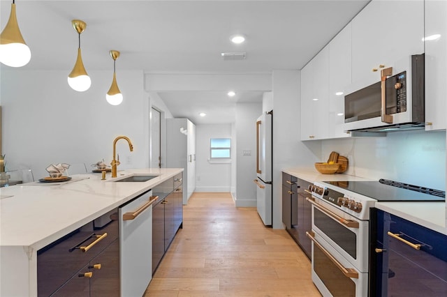 kitchen with white cabinetry, sink, stainless steel appliances, light hardwood / wood-style floors, and decorative light fixtures