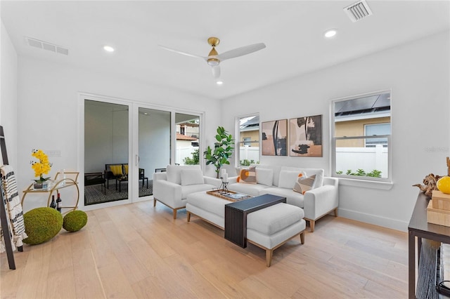 living room with light hardwood / wood-style flooring, ceiling fan, and a healthy amount of sunlight