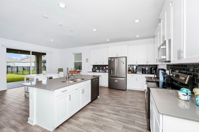 kitchen featuring a center island with sink, sink, white cabinets, and stainless steel appliances