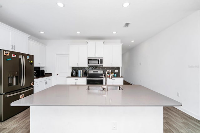 kitchen featuring a large island with sink, light hardwood / wood-style flooring, sink, white cabinetry, and appliances with stainless steel finishes