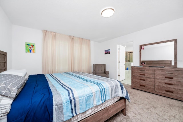 bedroom with connected bathroom and light colored carpet