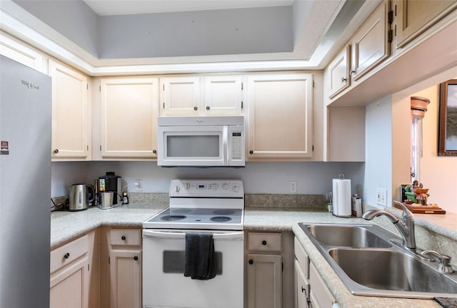 kitchen featuring white appliances, sink, and cream cabinets