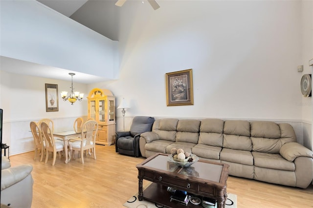 living room featuring ceiling fan with notable chandelier, light hardwood / wood-style flooring, and high vaulted ceiling