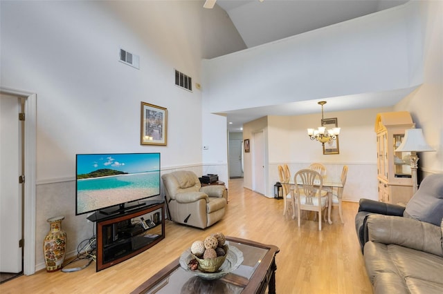 living room with high vaulted ceiling, an inviting chandelier, and hardwood / wood-style flooring