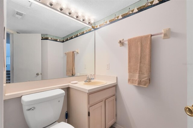 bathroom with vanity, a textured ceiling, and toilet