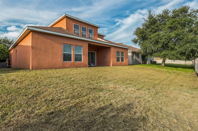 back of property with central AC unit and a yard