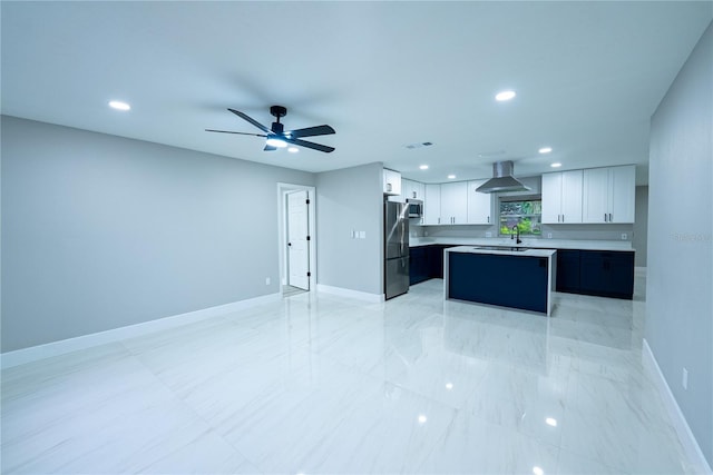 kitchen with stainless steel appliances, sink, a center island, white cabinets, and wall chimney range hood