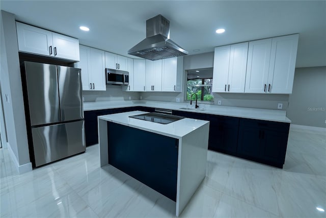 kitchen with white cabinetry, sink, appliances with stainless steel finishes, a kitchen island, and wall chimney range hood