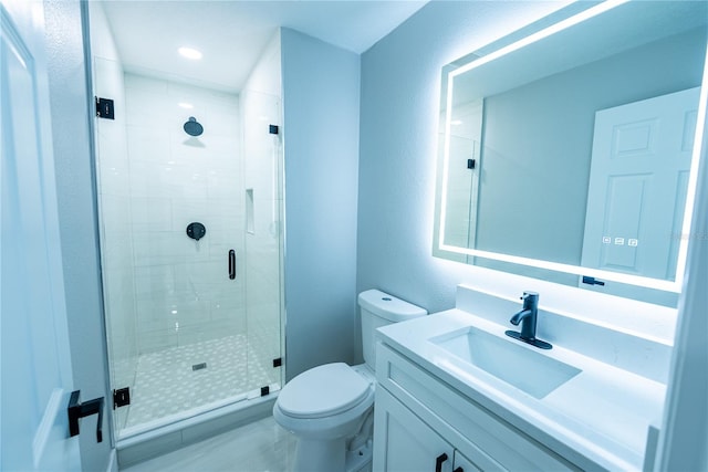 bathroom with toilet, vanity, and a shower with door