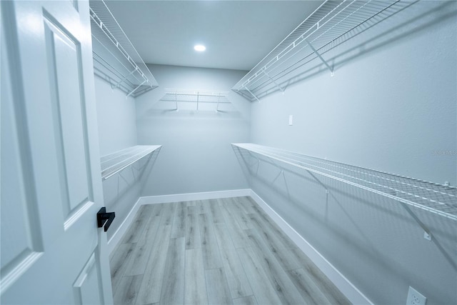 walk in closet with light hardwood / wood-style flooring