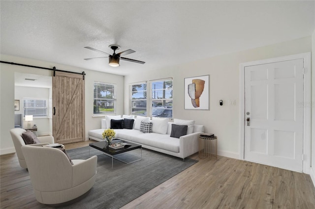 living room featuring a barn door, ceiling fan, a textured ceiling, and hardwood / wood-style floors