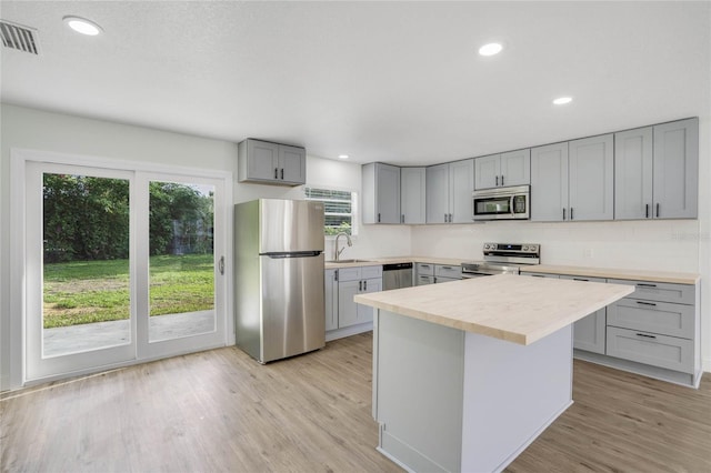 kitchen featuring light hardwood / wood-style floors, sink, appliances with stainless steel finishes, a center island, and gray cabinets