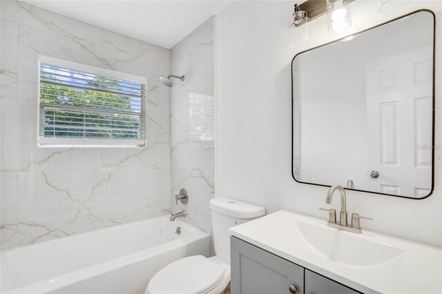 full bathroom featuring vanity, tiled shower / bath combo, and toilet