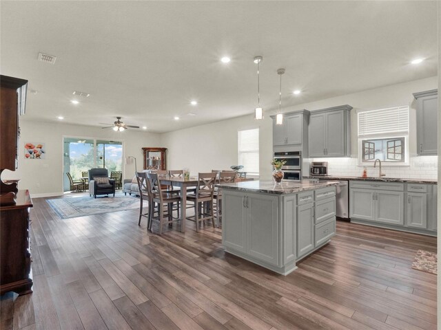 3286 Hanging Tide St, Winter Garden, FL 34787 - kitchen featuring a sink, gray cabinets, open floor plan, a kitchen island, and appliances with stainless steel finishes