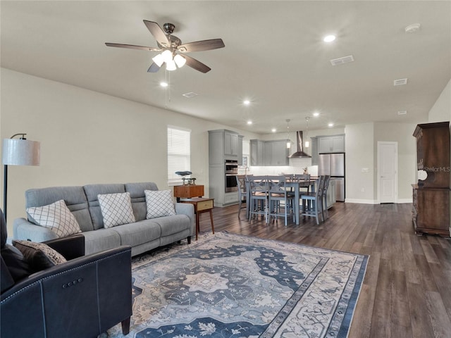 living room with dark wood-type flooring and ceiling fan