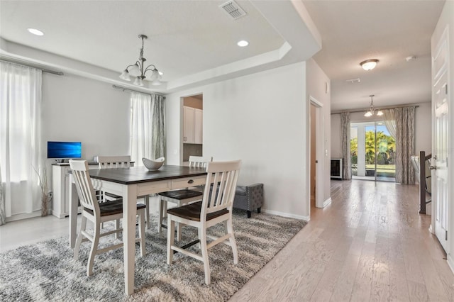 dining space featuring light wood-type flooring and a notable chandelier