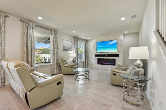 living room with a stone fireplace and light hardwood / wood-style flooring