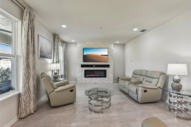 living room featuring a stone fireplace and light hardwood / wood-style flooring