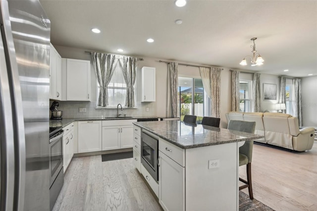 kitchen featuring white cabinets, a kitchen bar, a kitchen island, and appliances with stainless steel finishes