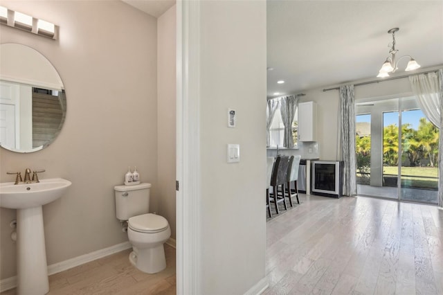 bathroom with hardwood / wood-style floors, a notable chandelier, sink, and toilet