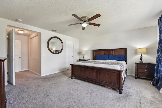 bedroom featuring a textured ceiling, light colored carpet, and ceiling fan