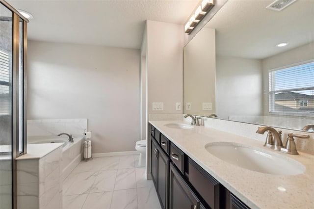 bathroom with toilet, vanity, and tiled bath