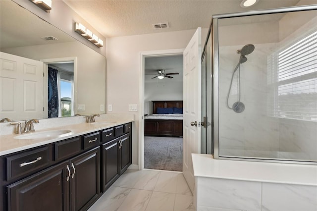 bathroom with vanity, a healthy amount of sunlight, a textured ceiling, and a tile shower