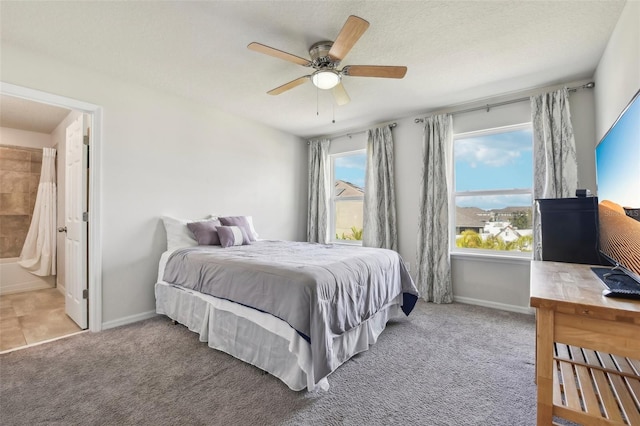 carpeted bedroom with ensuite bathroom, ceiling fan, and multiple windows