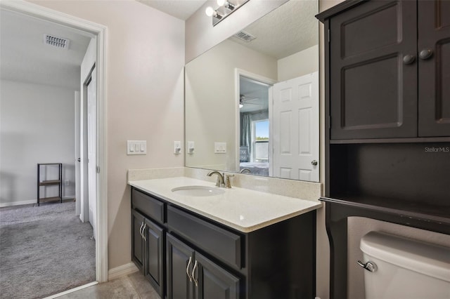 bathroom featuring ceiling fan, vanity, toilet, and a textured ceiling