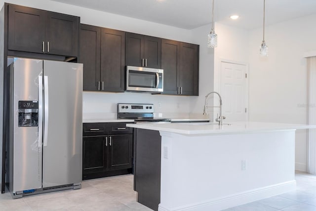 kitchen with hanging light fixtures, dark brown cabinets, stainless steel appliances, a center island with sink, and sink